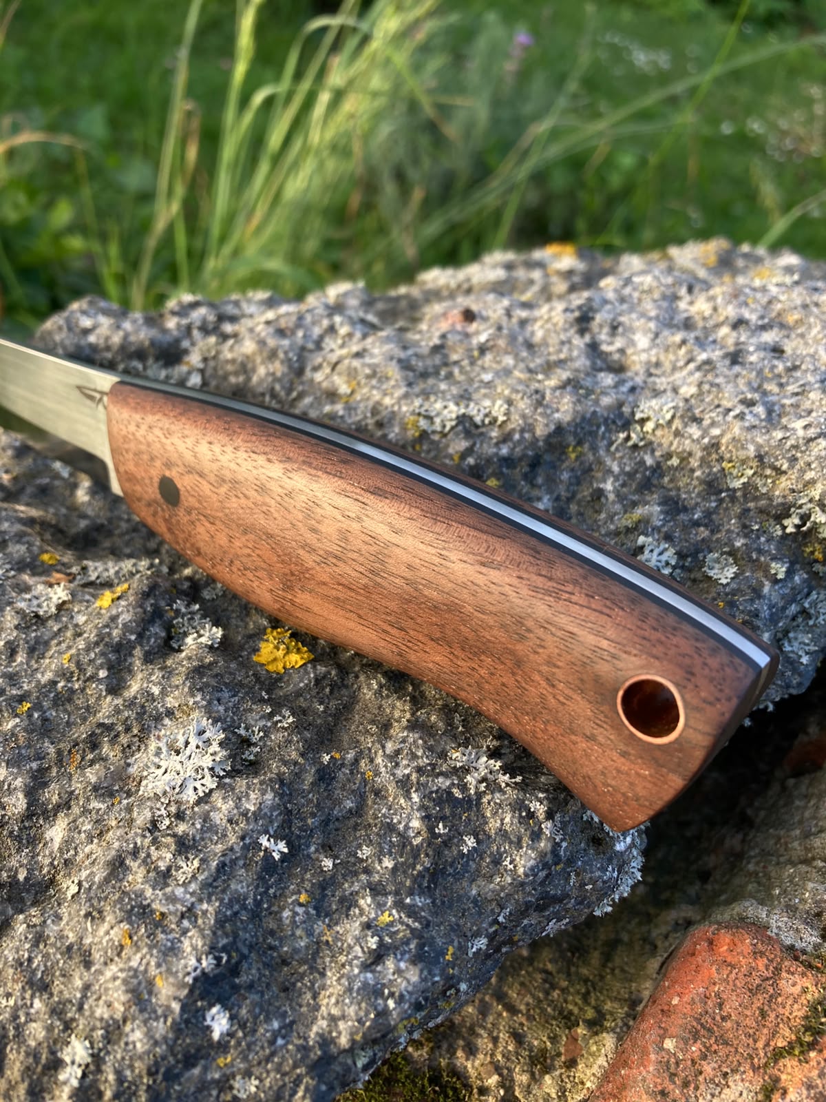 Close-up of walnut and G10 handle with copper lanyard tube