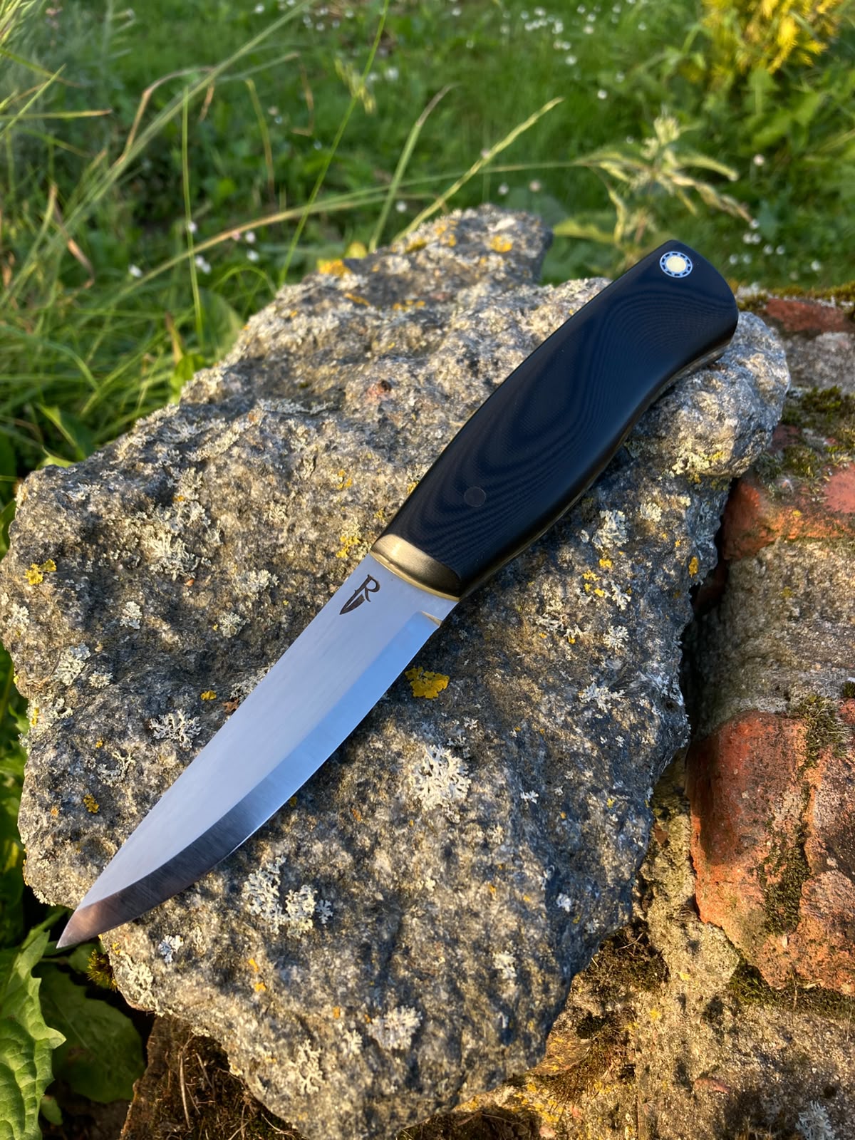 Bushcraft knife full blade view with brass bolster on stone