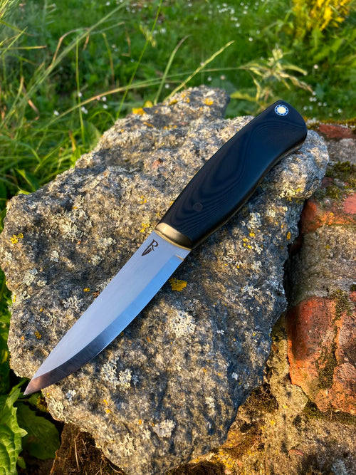 Bushcraft knife full blade view with brass bolster on stone