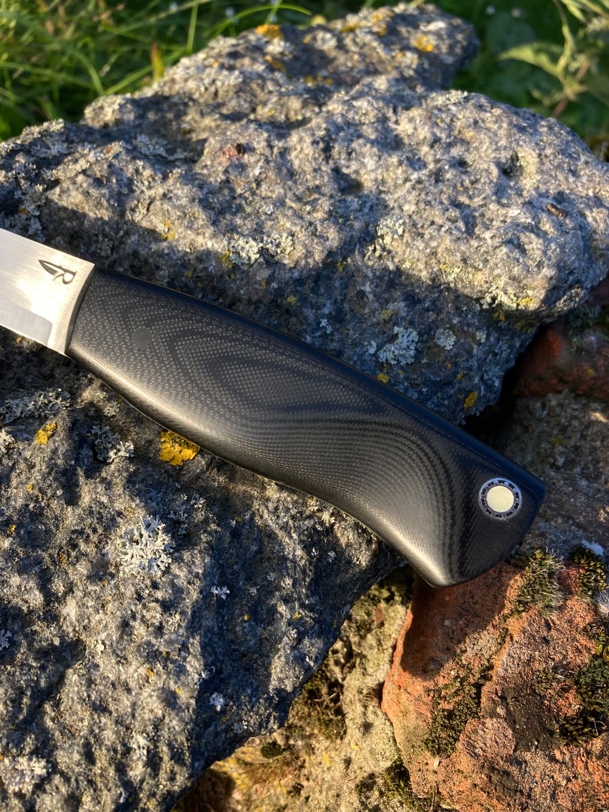 Close-up of black G10 handle texture with night glow mosaic pin