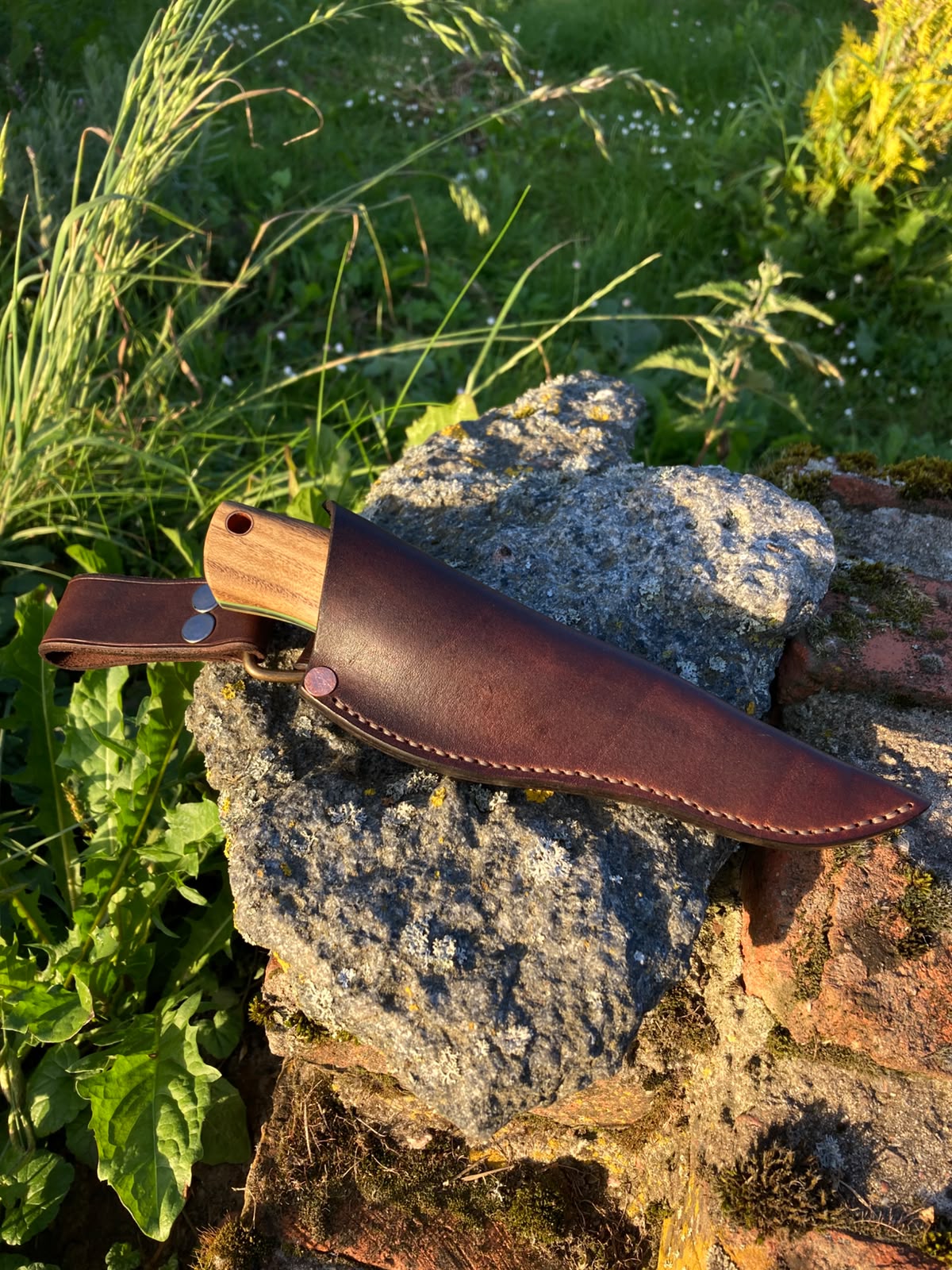 Bushcraft knife full view on stone in natural light